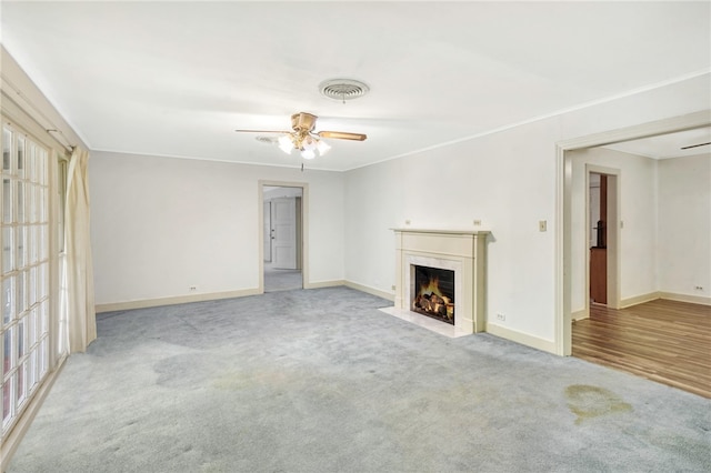 unfurnished living room featuring light colored carpet, ceiling fan, and crown molding