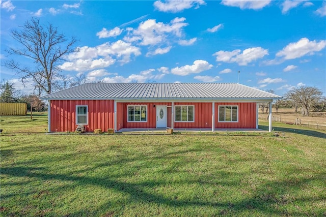 rear view of property featuring a yard, metal roof, and board and batten siding