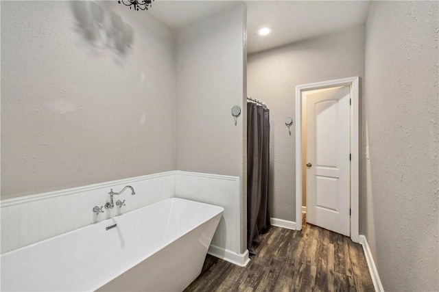 bathroom featuring a freestanding bath, wood finished floors, and baseboards
