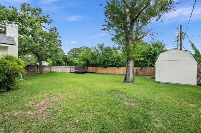 view of yard featuring a fenced backyard, an outbuilding, a shed, and a trampoline