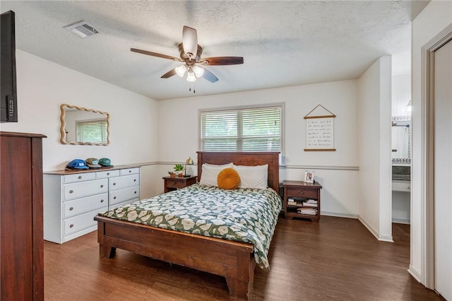 bedroom featuring ceiling fan, visible vents, a textured ceiling, and dark wood-type flooring
