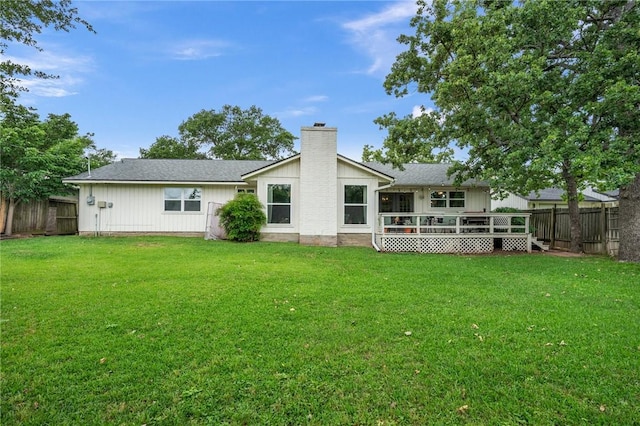 rear view of house with a lawn, a fenced backyard, a wooden deck, and a chimney