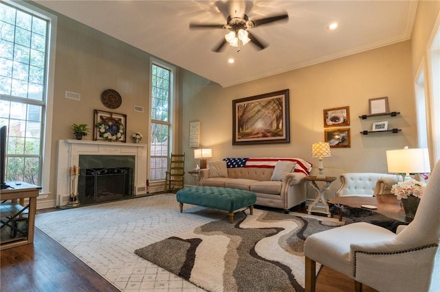 living room with wood-type flooring, ceiling fan, and ornamental molding