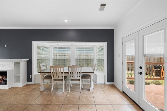 dining area with light tile patterned floors, crown molding, and french doors