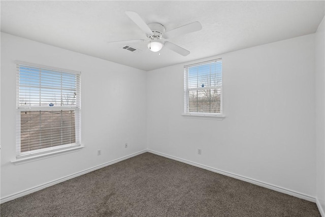 empty room featuring ceiling fan and dark colored carpet