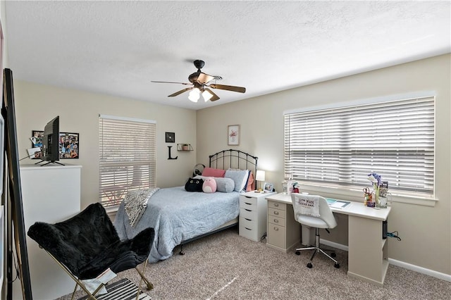 bedroom with a textured ceiling, multiple windows, a ceiling fan, and light carpet