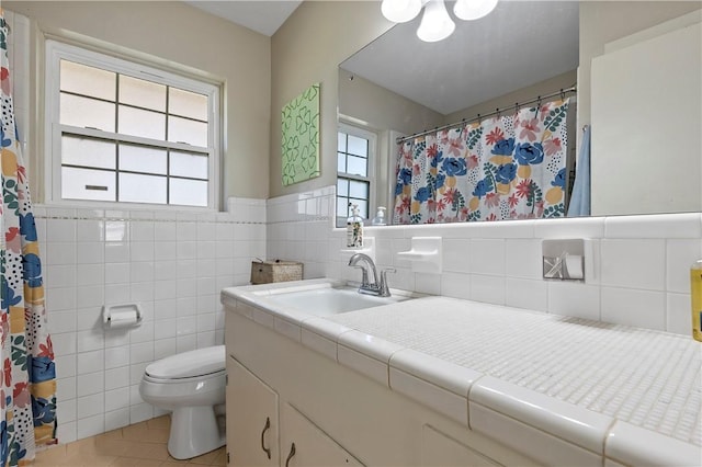 full bath with a wainscoted wall, toilet, tile walls, tile patterned flooring, and vanity