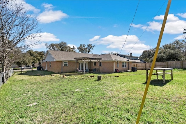 rear view of property with brick siding, a lawn, a pergola, and a fenced backyard