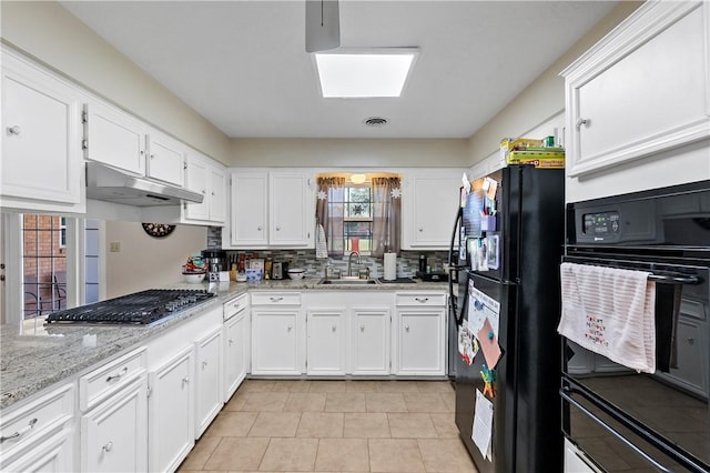 kitchen with a skylight, a sink, black appliances, white cabinets, and under cabinet range hood