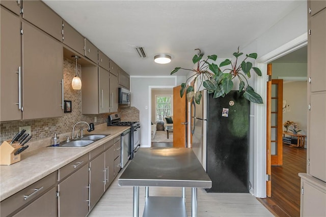 1103 Edgewood Dr, Bryan, TX 77802 - kitchen featuring stainless steel appliances, light wood-type flooring, decorative backsplash, light countertops, and gray cabinets