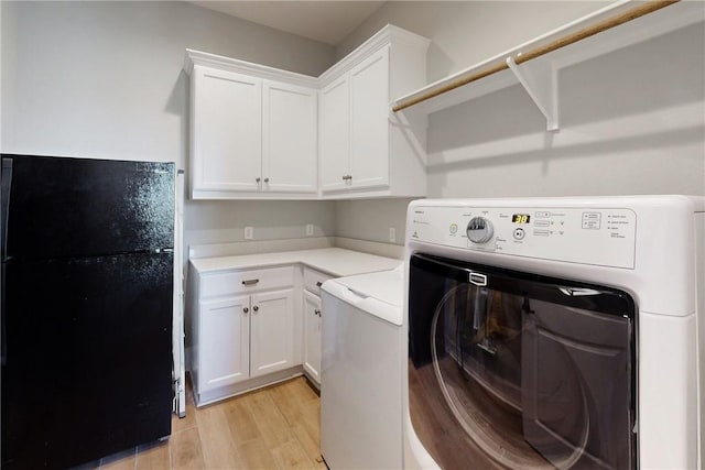 washroom with washer / dryer, light wood-type flooring, and cabinet space