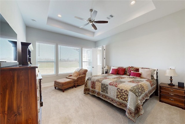 bedroom with a raised ceiling, light carpet, visible vents, and baseboards