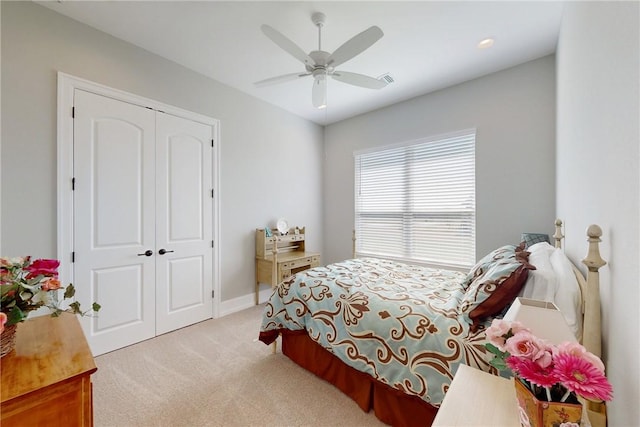 bedroom with a closet, a ceiling fan, and light colored carpet