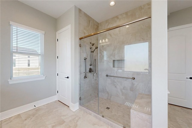 bathroom with marble finish floor, a stall shower, and baseboards