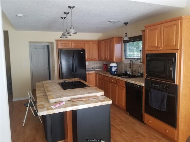 231 Memphis Belle Ln, Trinity, TX 75862 - kitchen featuring black appliances, a sink, tile countertops, light wood finished floors, and decorative backsplash