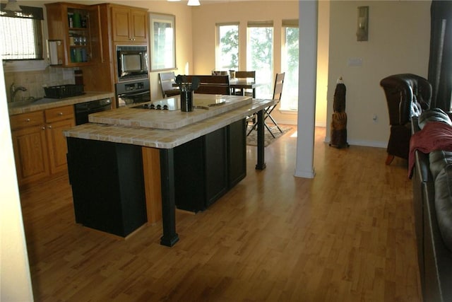 231 Memphis Belle Ln, Trinity, TX 75862 - kitchen featuring black appliances, tile counters, light wood-style flooring, and baseboards