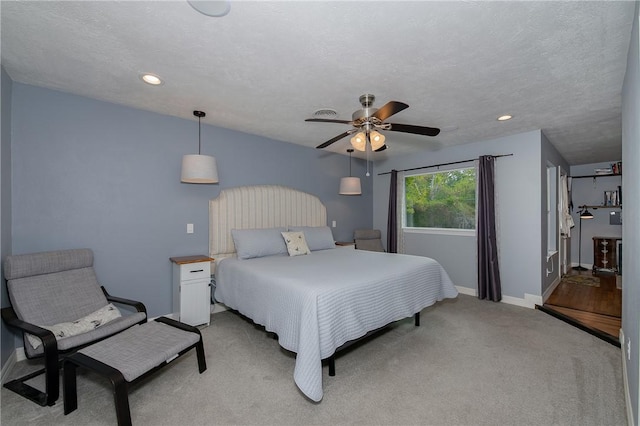 carpeted bedroom with ceiling fan and a textured ceiling