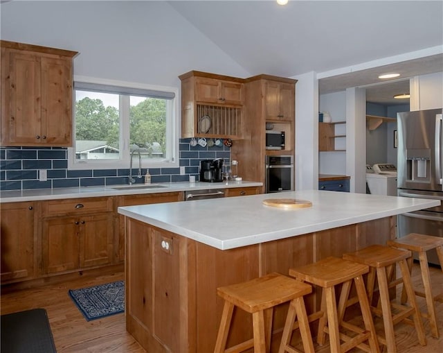 kitchen featuring a kitchen bar, stainless steel appliances, tasteful backsplash, and washing machine and clothes dryer