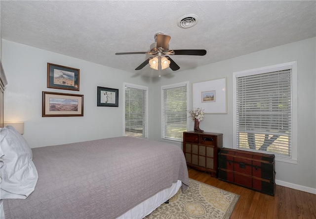 bedroom featuring ceiling fan, dark hardwood / wood-style flooring, and a textured ceiling