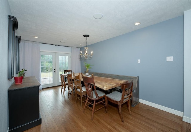 dining space featuring french doors, a textured ceiling, dark hardwood / wood-style floors, and an inviting chandelier