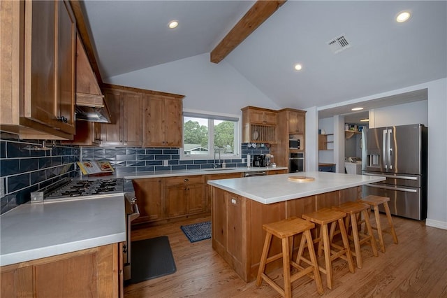 kitchen with a center island, lofted ceiling with beams, decorative backsplash, light wood-type flooring, and stainless steel appliances