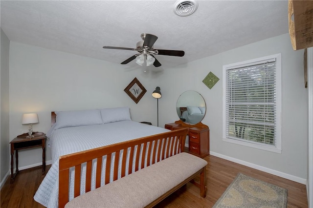 bedroom featuring a textured ceiling, ceiling fan, and dark hardwood / wood-style floors