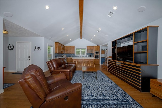 living room with vaulted ceiling with beams and light hardwood / wood-style floors