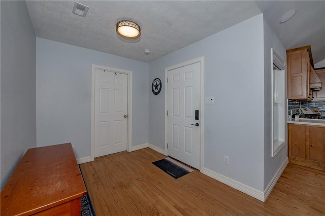 foyer entrance with a textured ceiling and light wood-type flooring