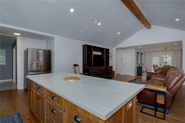 kitchen with hardwood / wood-style flooring, a notable chandelier, stainless steel fridge with ice dispenser, vaulted ceiling with beams, and a kitchen island