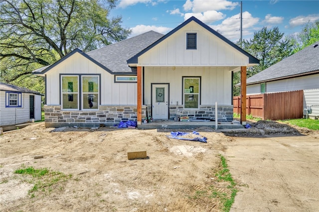 1403 Clark St, Bryan, TX 77808 - modern inspired farmhouse with covered porch, stone siding, roof with shingles, board and batten siding, and fence