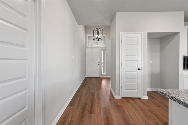 hallway with dark hardwood / wood-style flooring and a chandelier