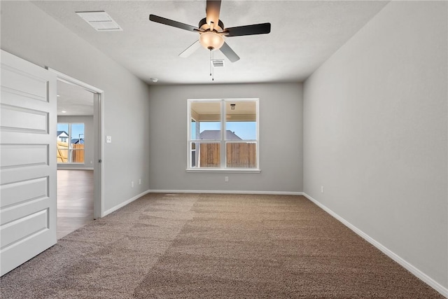 empty room with ceiling fan, carpet floors, and a wealth of natural light