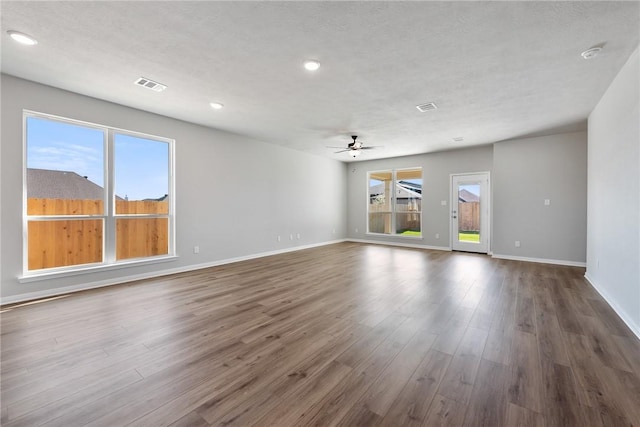 empty room featuring dark hardwood / wood-style floors, ceiling fan, a textured ceiling, and a wealth of natural light