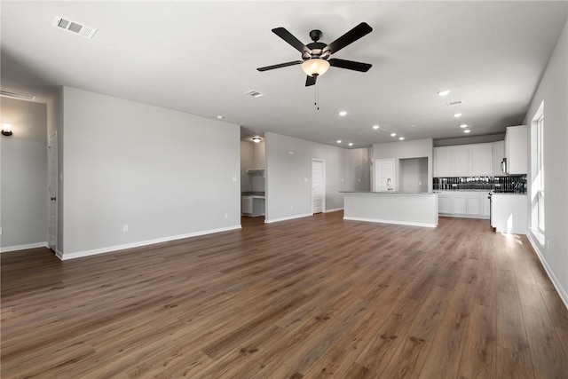 unfurnished living room featuring ceiling fan and dark wood-type flooring