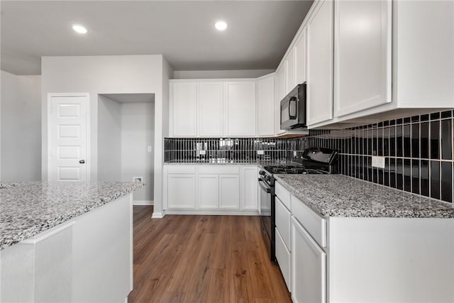 kitchen with hardwood / wood-style floors, black appliances, white cabinets, decorative backsplash, and light stone countertops