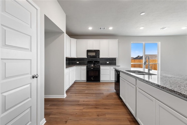 kitchen with black appliances, sink, light stone counters, dark hardwood / wood-style flooring, and white cabinetry