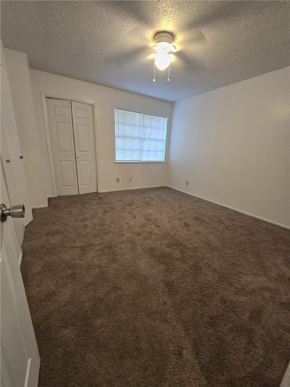 unfurnished room with a textured ceiling and dark colored carpet