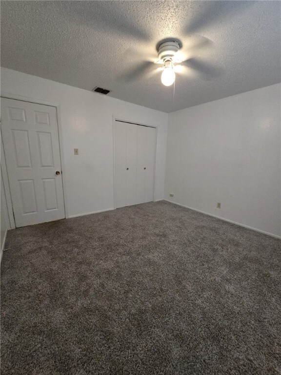 unfurnished bedroom featuring ceiling fan, carpet floors, and a textured ceiling