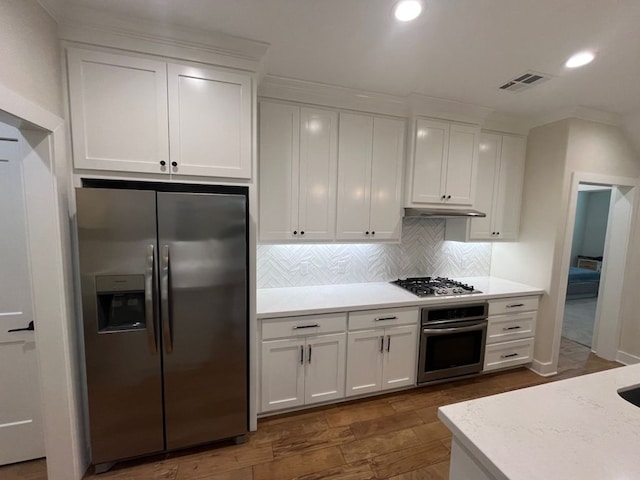 2016 R A Galindo Blvd, Bryan, TX 77807 - kitchen with appliances with stainless steel finishes, white cabinetry, backsplash, under cabinet range hood, and recessed lighting