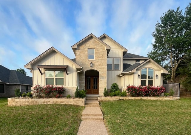 2016 R A Galindo Blvd, Bryan, TX 77807 - view of front of home featuring board and batten siding, stone siding, a front yard, and french doors