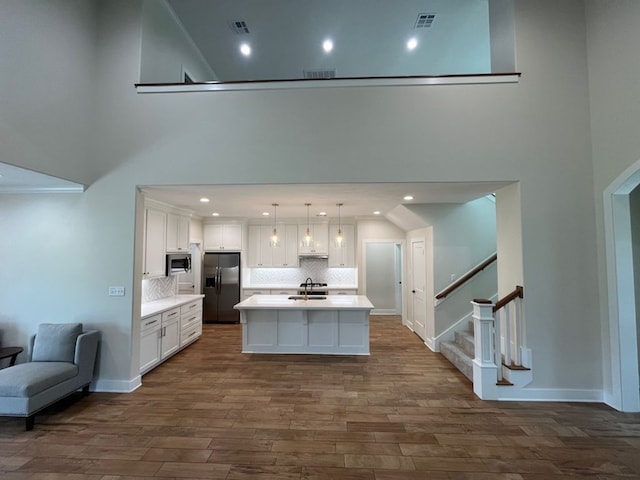 2016 R A Galindo Blvd, Bryan, TX 77807 - kitchen with stainless steel appliances, a sink, white cabinetry, light countertops, and a high ceiling