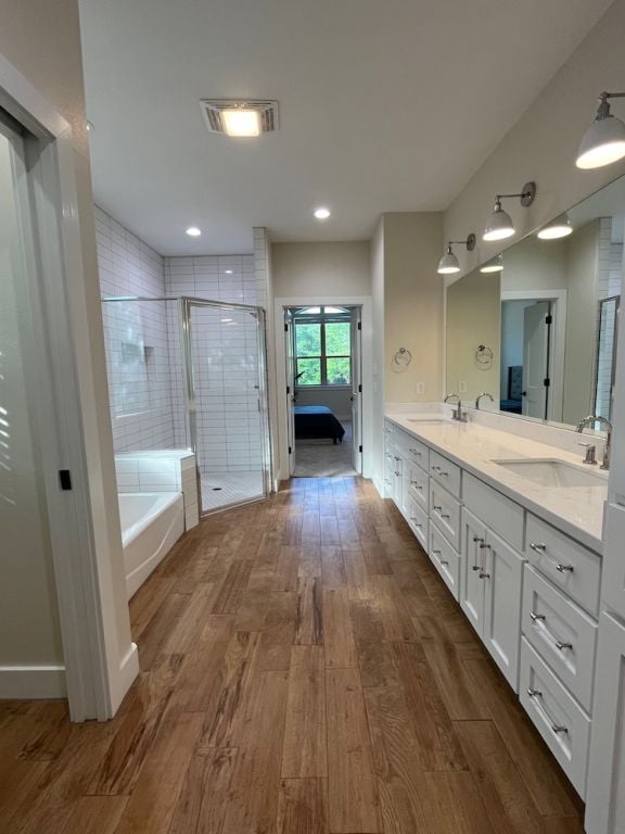 2016 R A Galindo Blvd, Bryan, TX 77807 - bathroom featuring wood finished floors, a tub, a shower stall, and double vanity