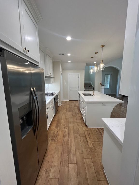 2016 R A Galindo Blvd, Bryan, TX 77807 - kitchen featuring stainless steel appliances, a sink, wood finished floors, white cabinetry, and recessed lighting