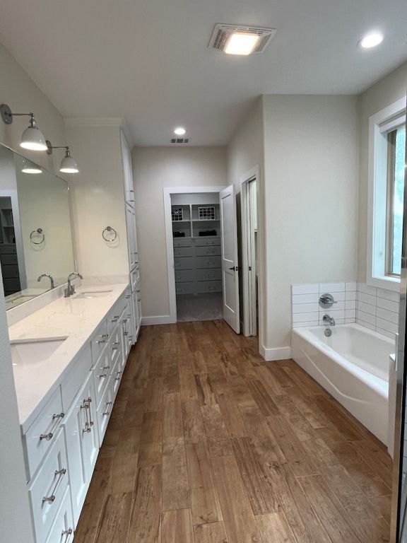 2016 R A Galindo Blvd, Bryan, TX 77807 - bathroom with wood finished floors, a bath, baseboards, a spacious closet, and double vanity