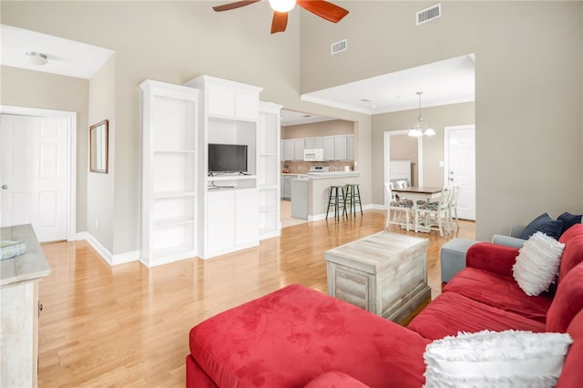 living room featuring baseboards, visible vents, light wood-style flooring, and ceiling fan with notable chandelier