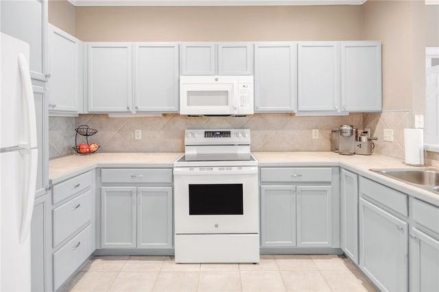 kitchen with a sink, white appliances, light countertops, light tile patterned floors, and backsplash