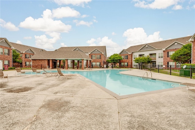 community pool featuring fence, a patio area, and a residential view