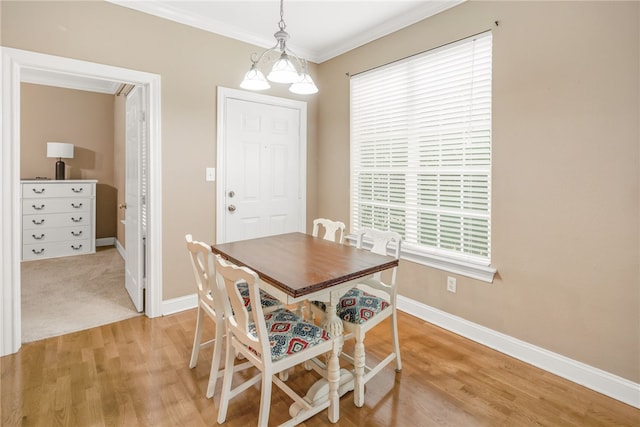 dining space with baseboards, ornamental molding, and light wood finished floors