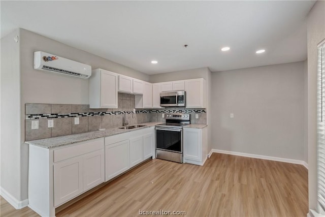 kitchen with white cabinetry, sink, stainless steel appliances, light hardwood / wood-style flooring, and an AC wall unit