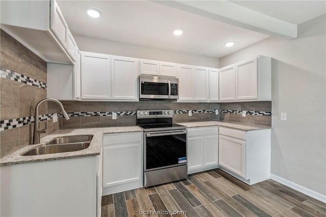 kitchen featuring appliances with stainless steel finishes, tasteful backsplash, dark wood-type flooring, sink, and white cabinets